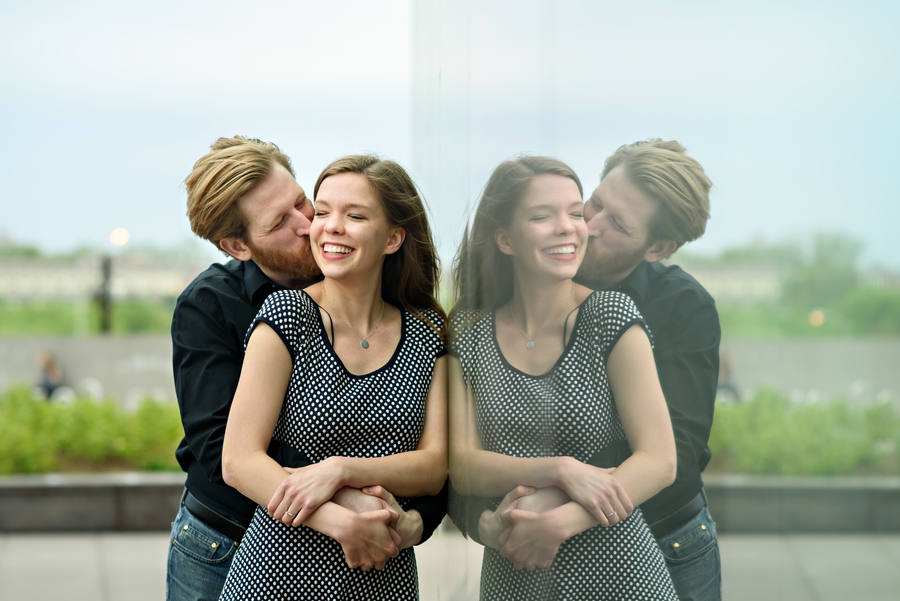 A couple kiss in the reflection of a giant window at cira green in west philly.